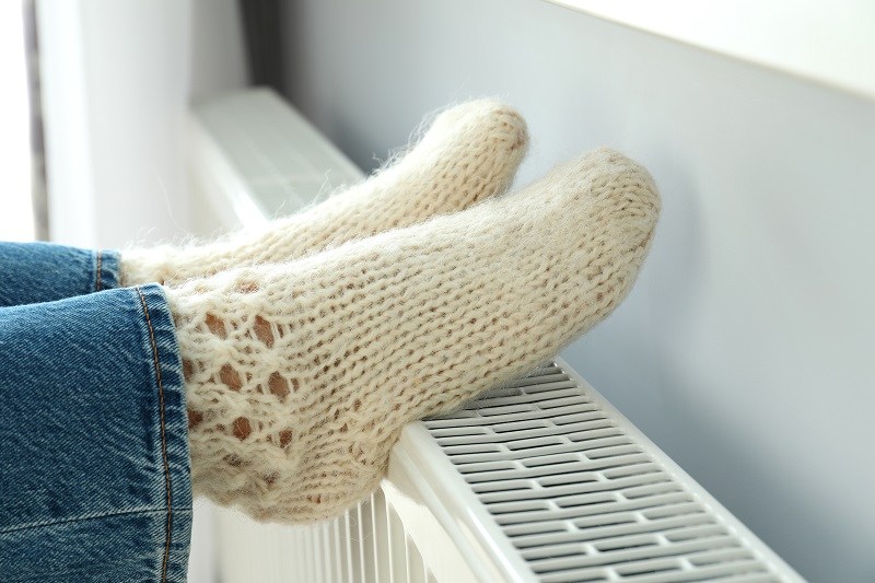 жена топли своите стъпала на радиатор